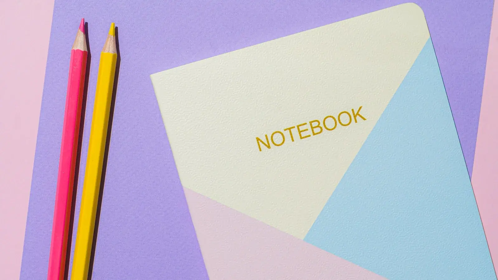 Pastel notebooks and pencils laid out for school.