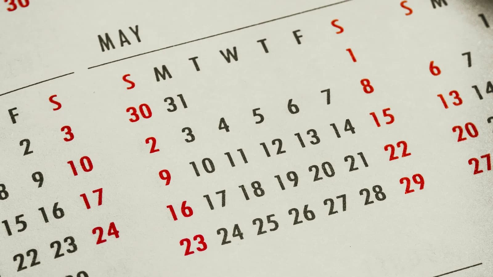 Close-up of a printed wall calendar showing the May monthly grid with weekday headers and date numbers in black and red type.