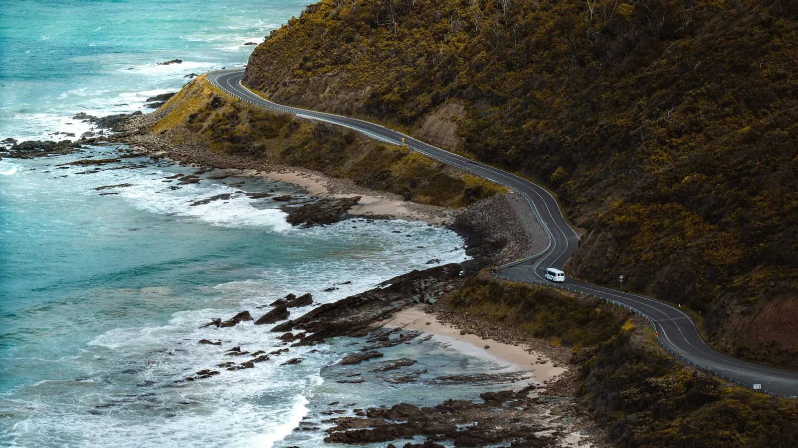 The Great Ocean Road winding around a green coastal headland.