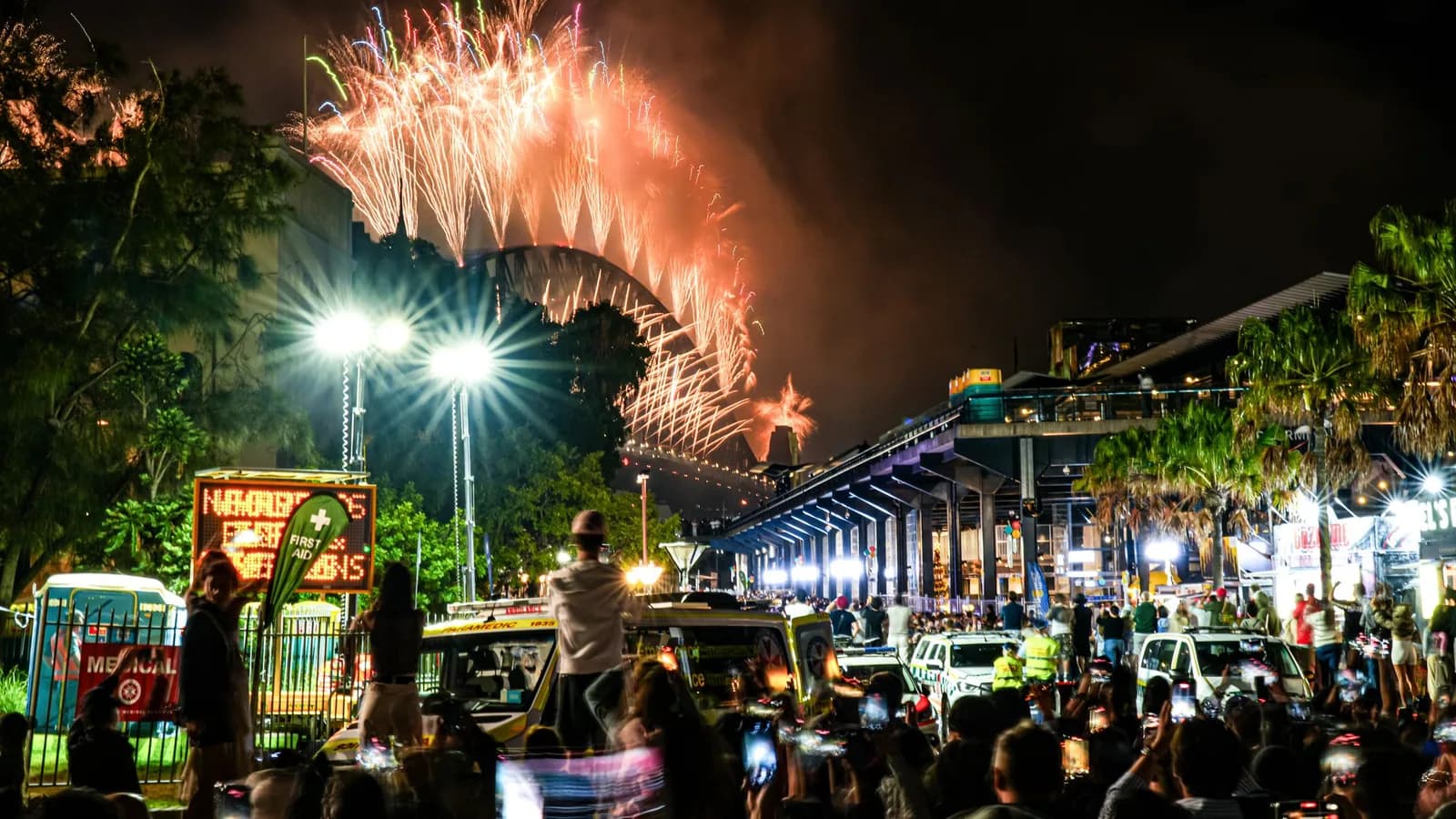 Fireworks lighting up the Sydney Harbour Bridge above a crowd.