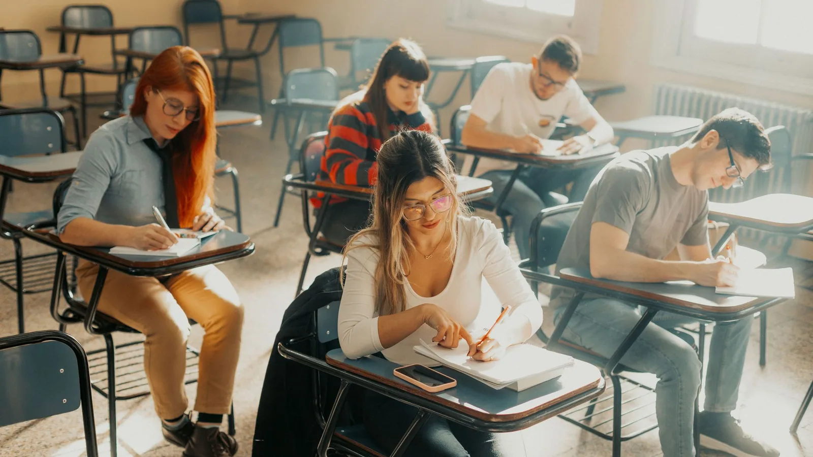 Students sitting at individual desks in an examination room.