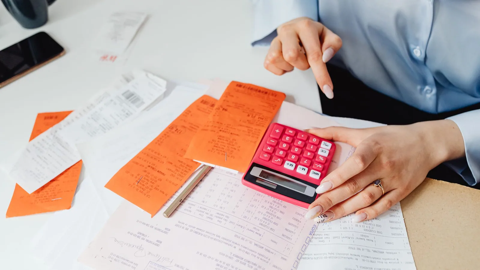 A red calculator and pen resting on financial paperwork.