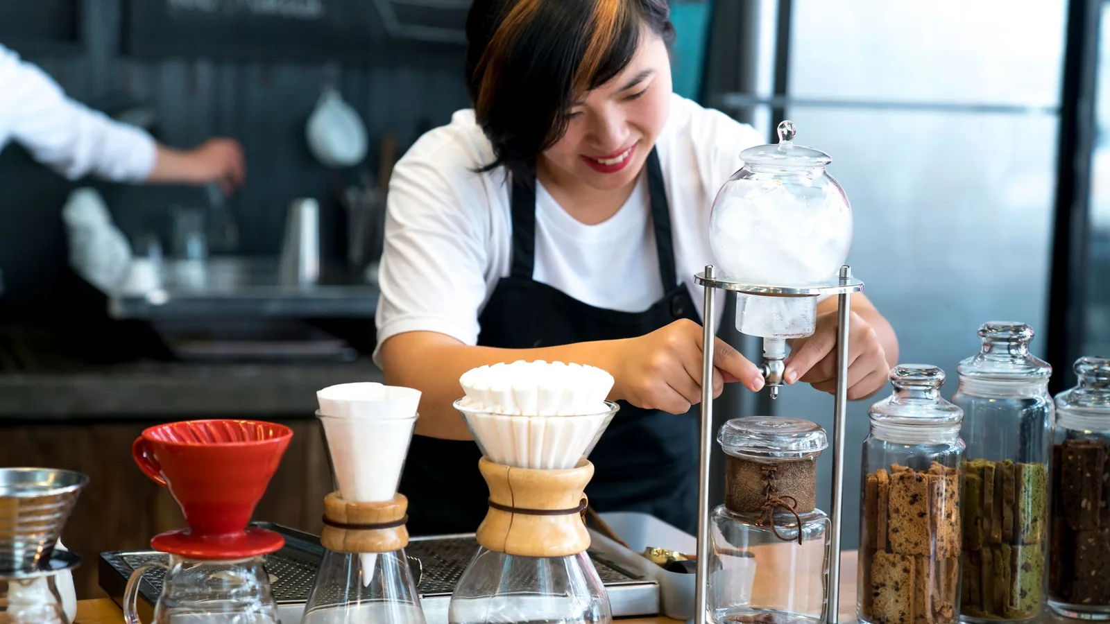 A barista preparing coffee behind a cafe counter.