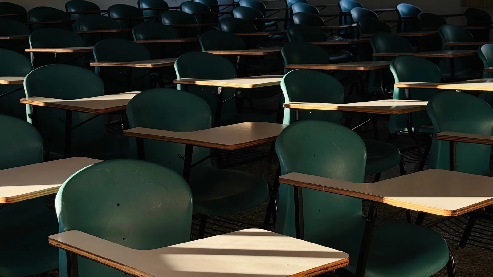 Sunlight falling across rows of green classroom chairs and desks.