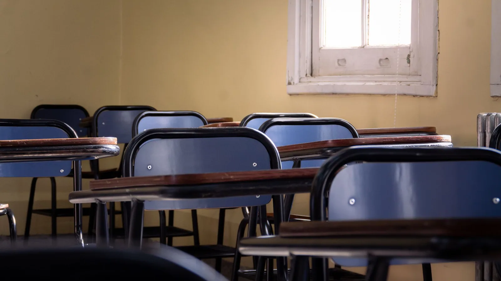 Rows of blue chairs and writing desks in an empty classroom.