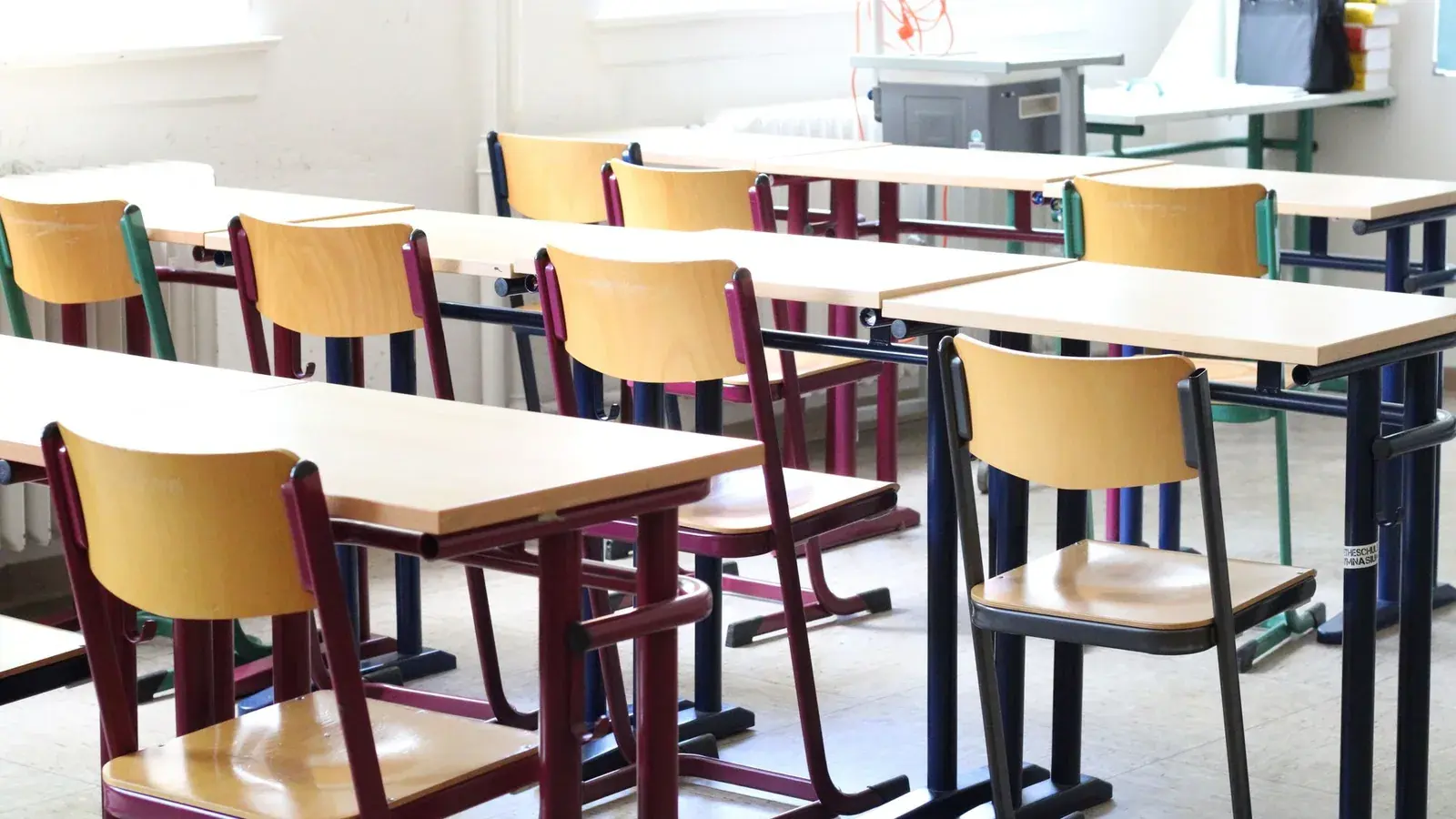 Rows of desks and chairs in a bright, empty classroom.