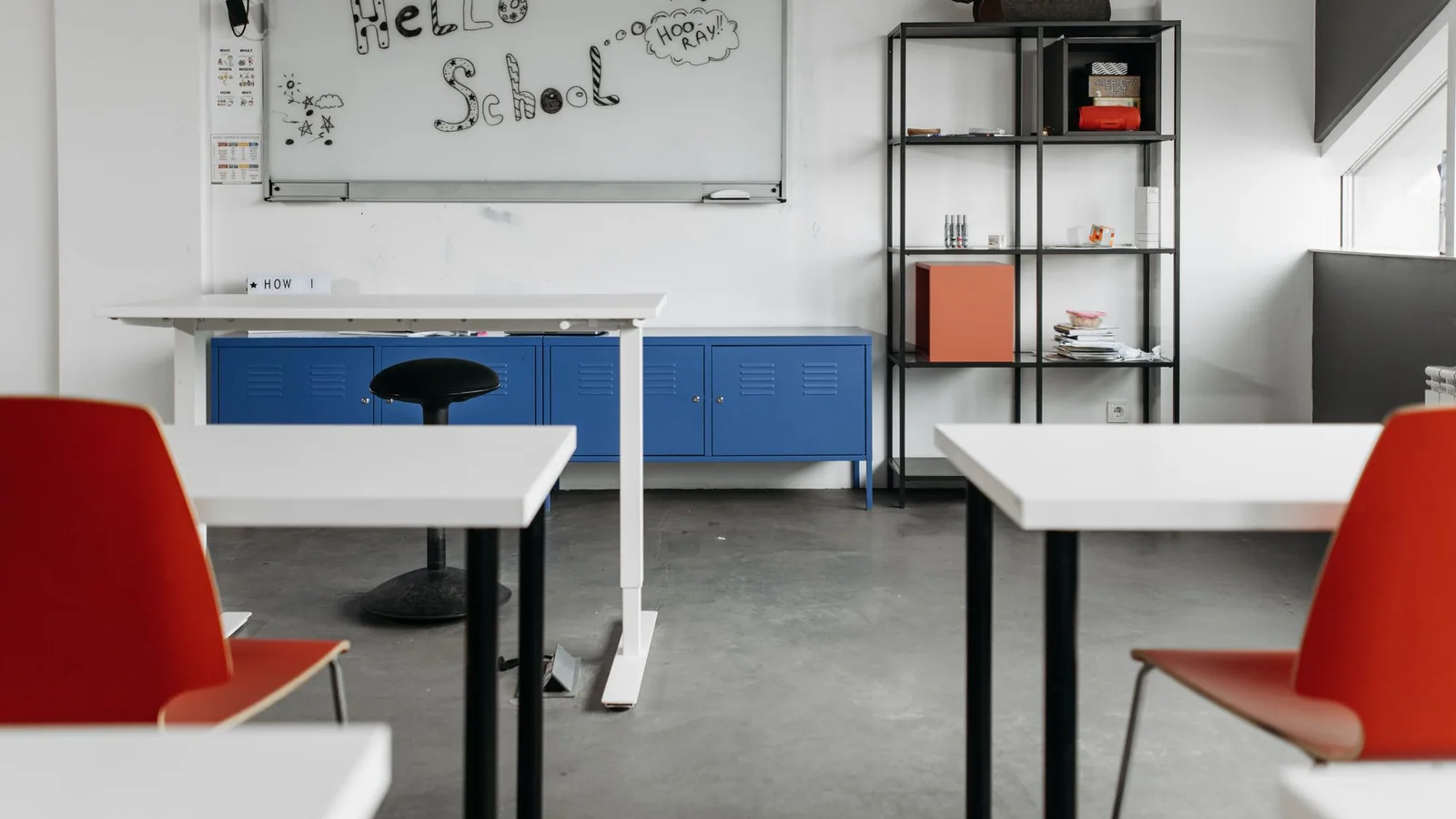 White classroom tables and red chairs facing a whiteboard.