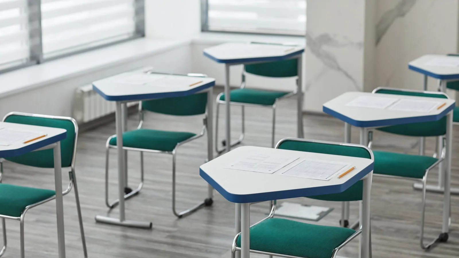 Papers on individual classroom desks beside a window.